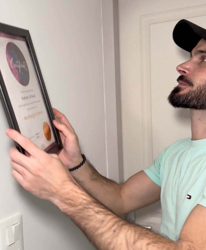 Un homme ajuste un certificat d’étoile encadré sur un mur.