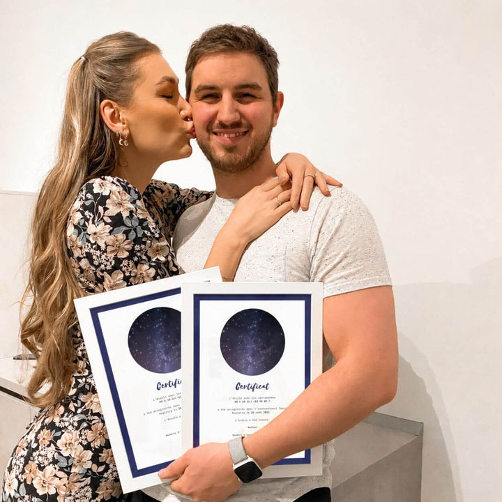 Une femme embrasse un homme qui tient deux certificats d’étoiles.